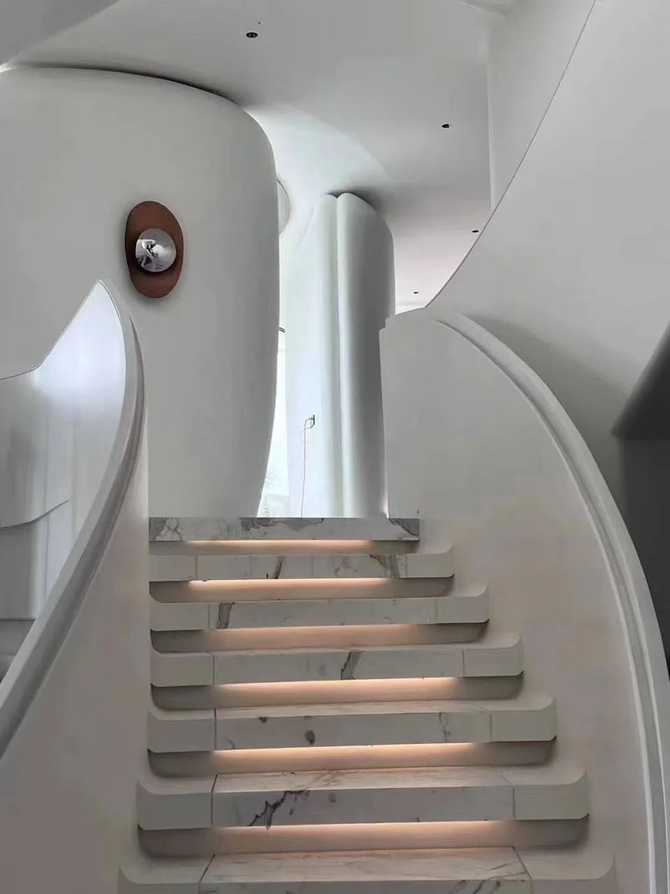 Sculptural marble staircase with lit treads