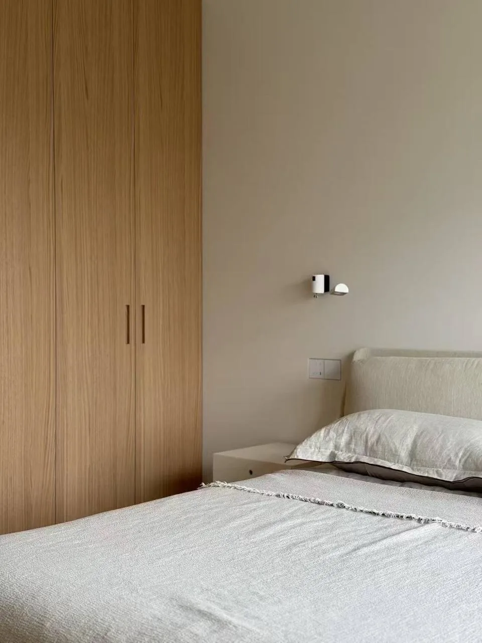Custom oak full-height wardrobe beside a bed